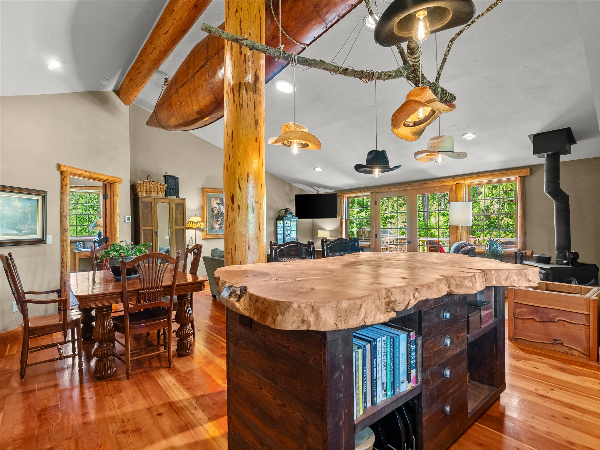 Rustic kitchen and dining area with a live-edge island, exposed beams, and large garden-facing windows.