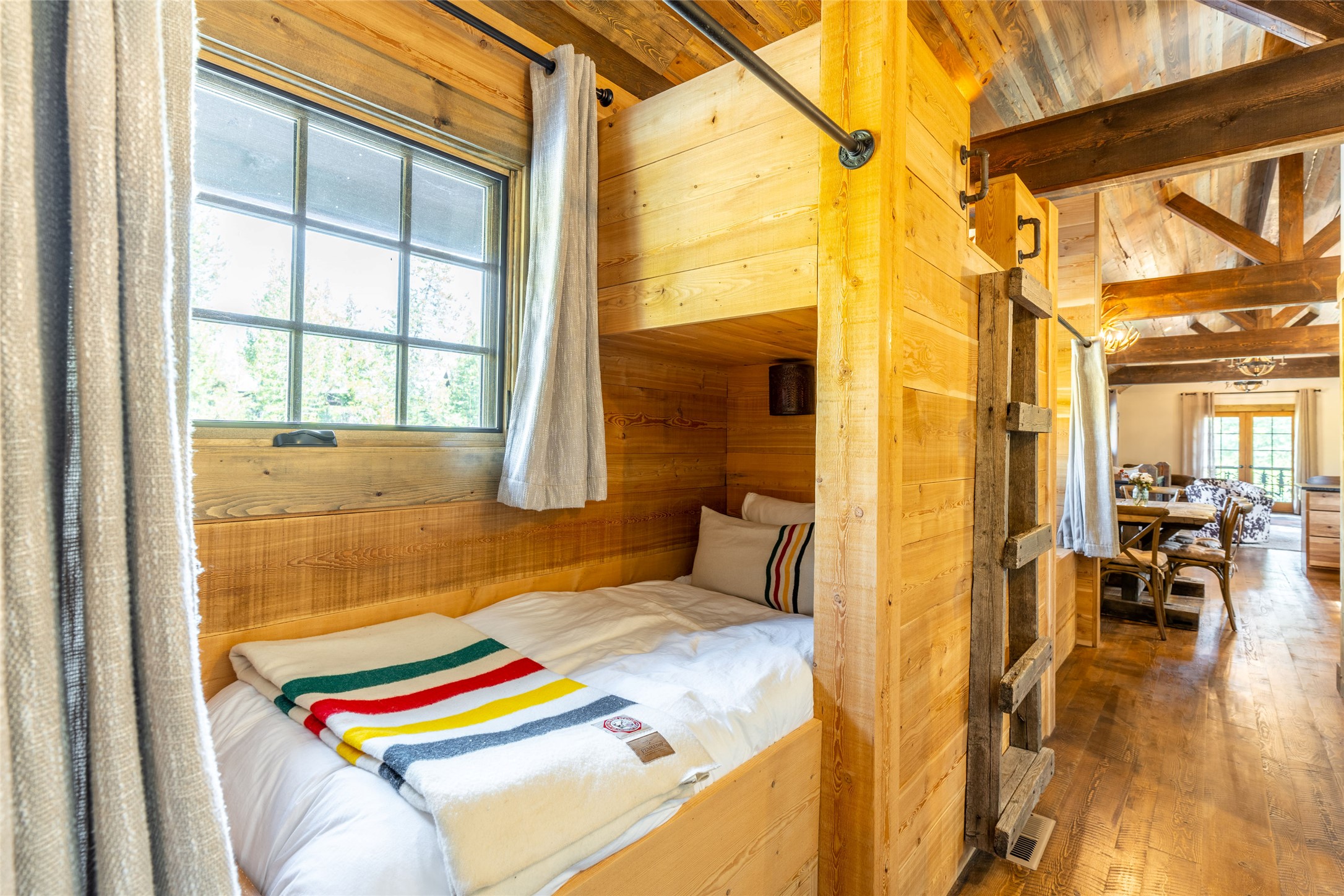 Rustic cabin bedroom with a built-in wooden sleeping alcove and a colorful striped blanket.
