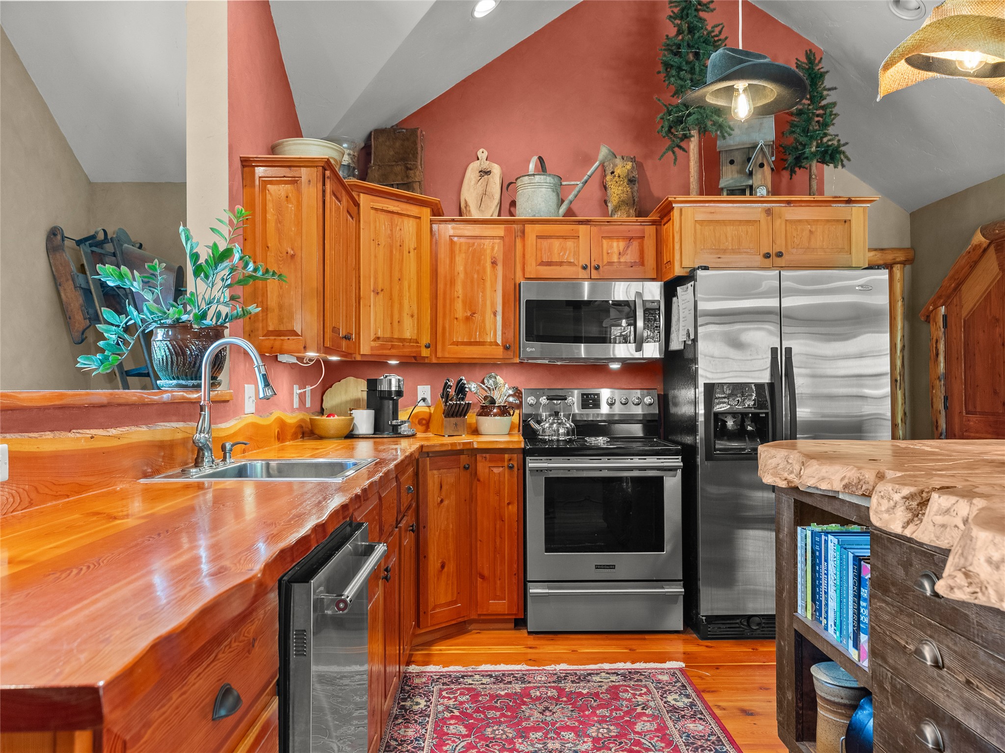Rustic kitchen with knotty-pine cabinetry, stainless steel appliances, and a live-edge island.