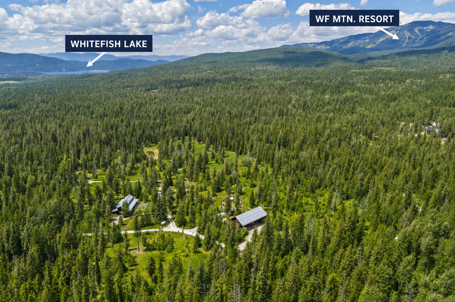 Aerial view of forested property with Whitefish Lake and Whitefish Mountain Resort in the distance.