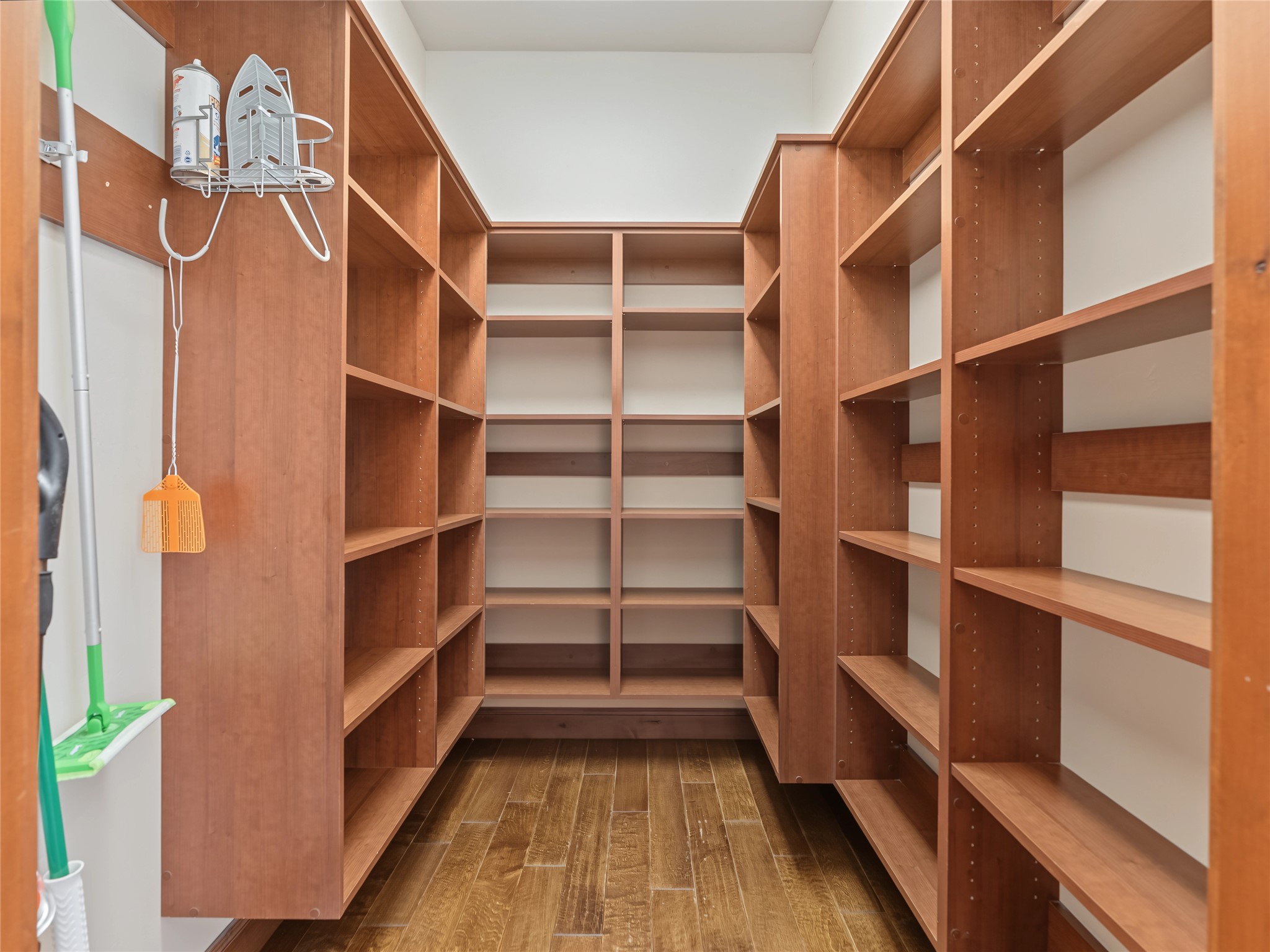 Walk-in closet lined with built-in wood shelving and wood-look flooring.