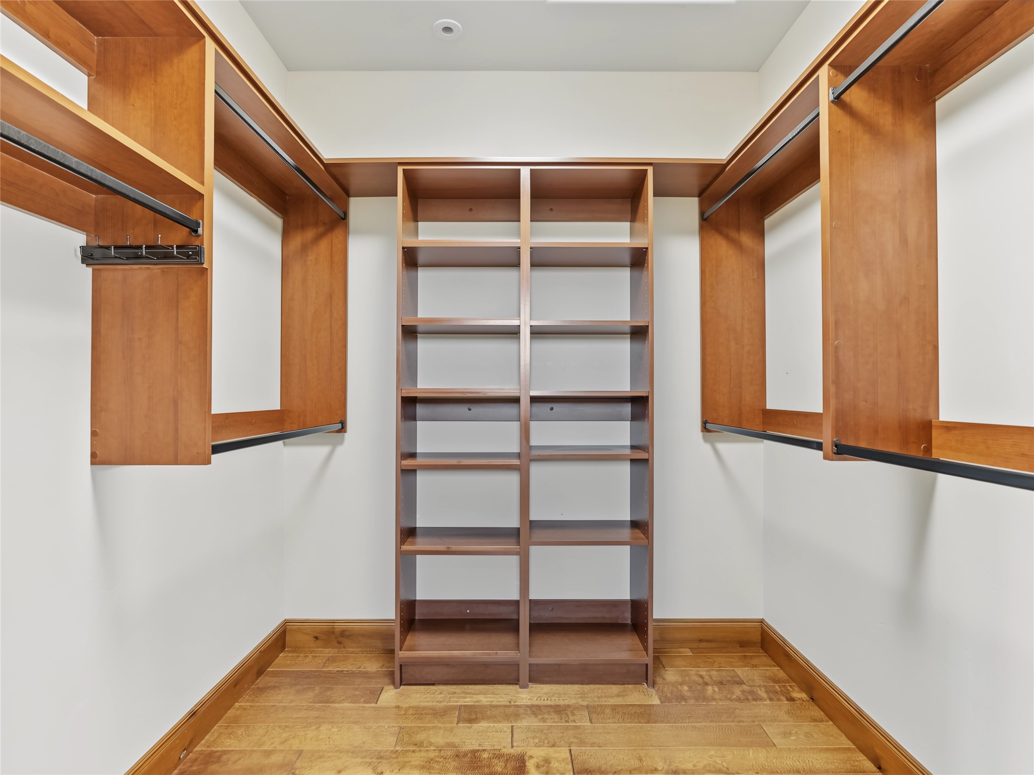 Walk-in closet with built-in wood shelving and clothes rails along both sides.