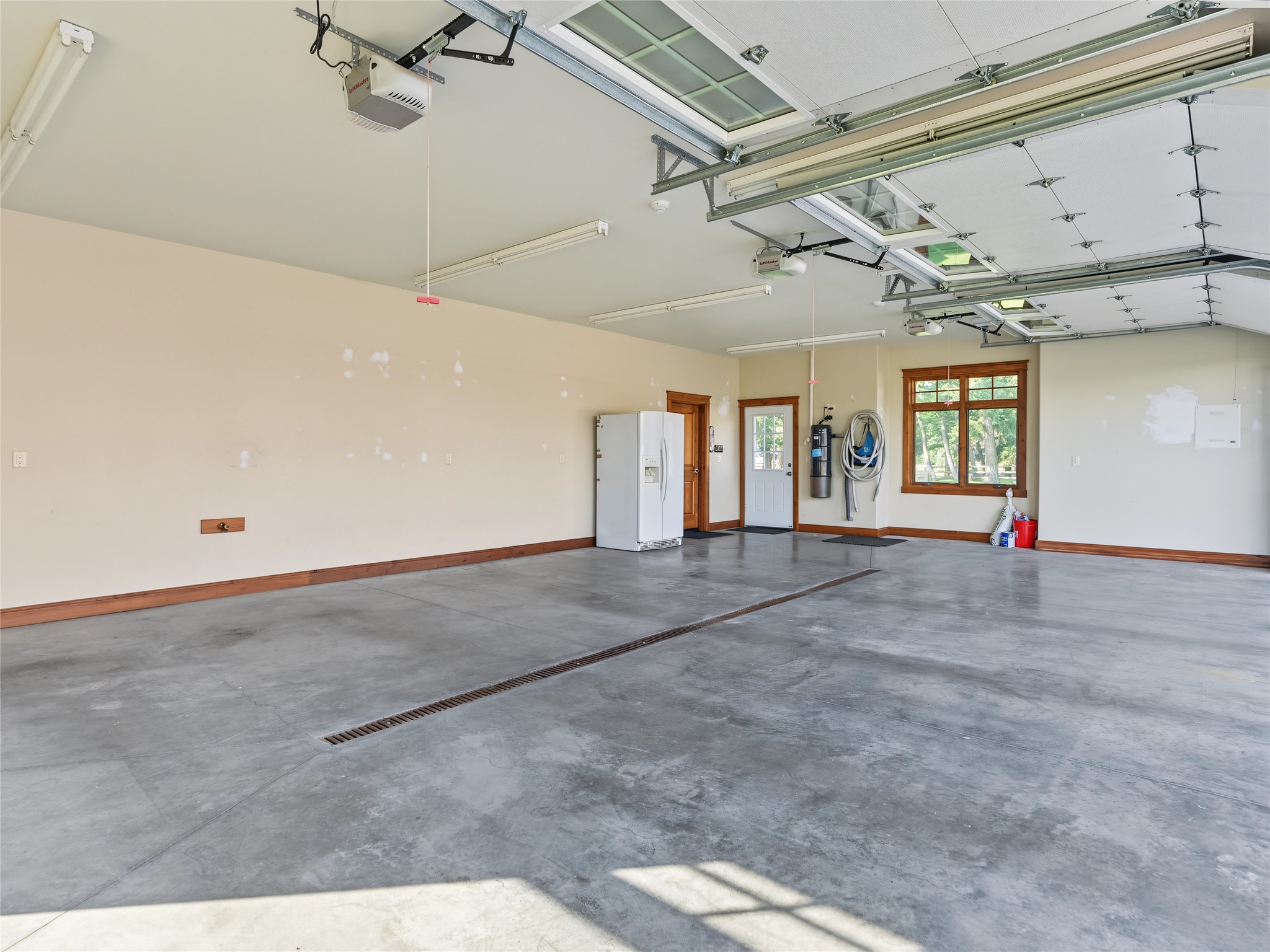 Spacious garage with a concrete floor, long drain, and multiple windowed overhead doors.