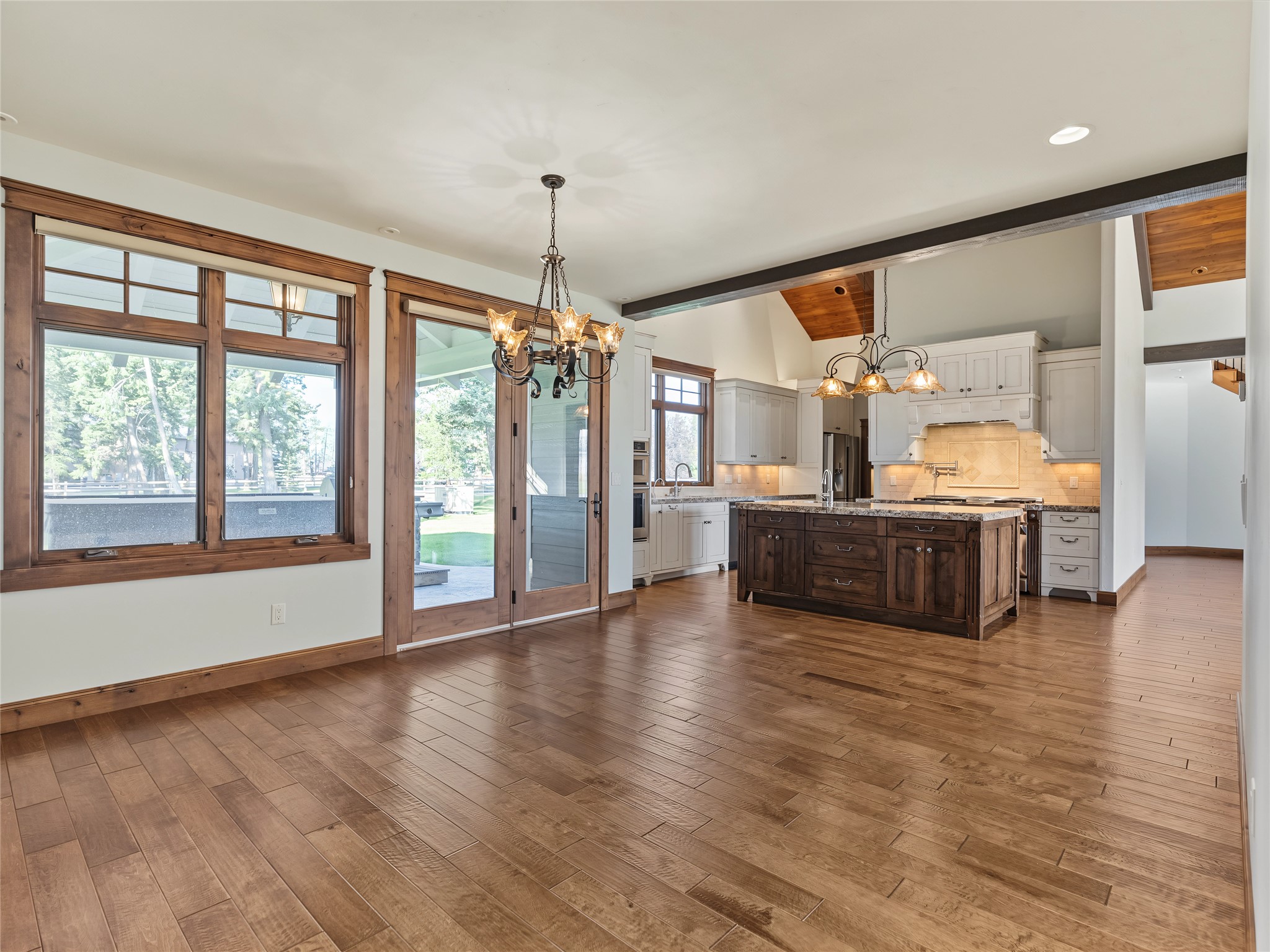 Open kitchen with a dark wood island, white cabinets, and large windows overlooking the yard.