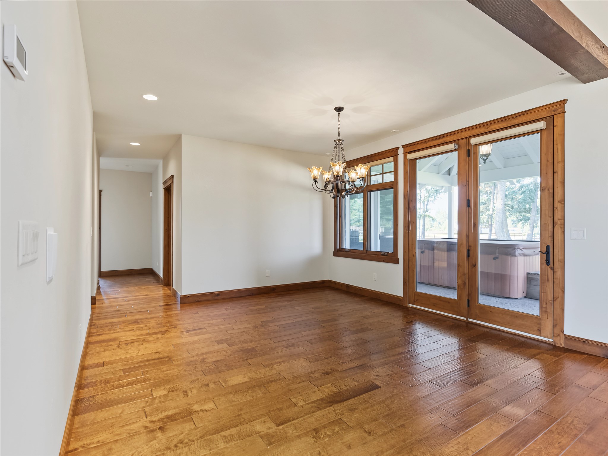 Empty dining room with hardwood floors, a chandelier, and glass doors overlooking a patio hot tub.