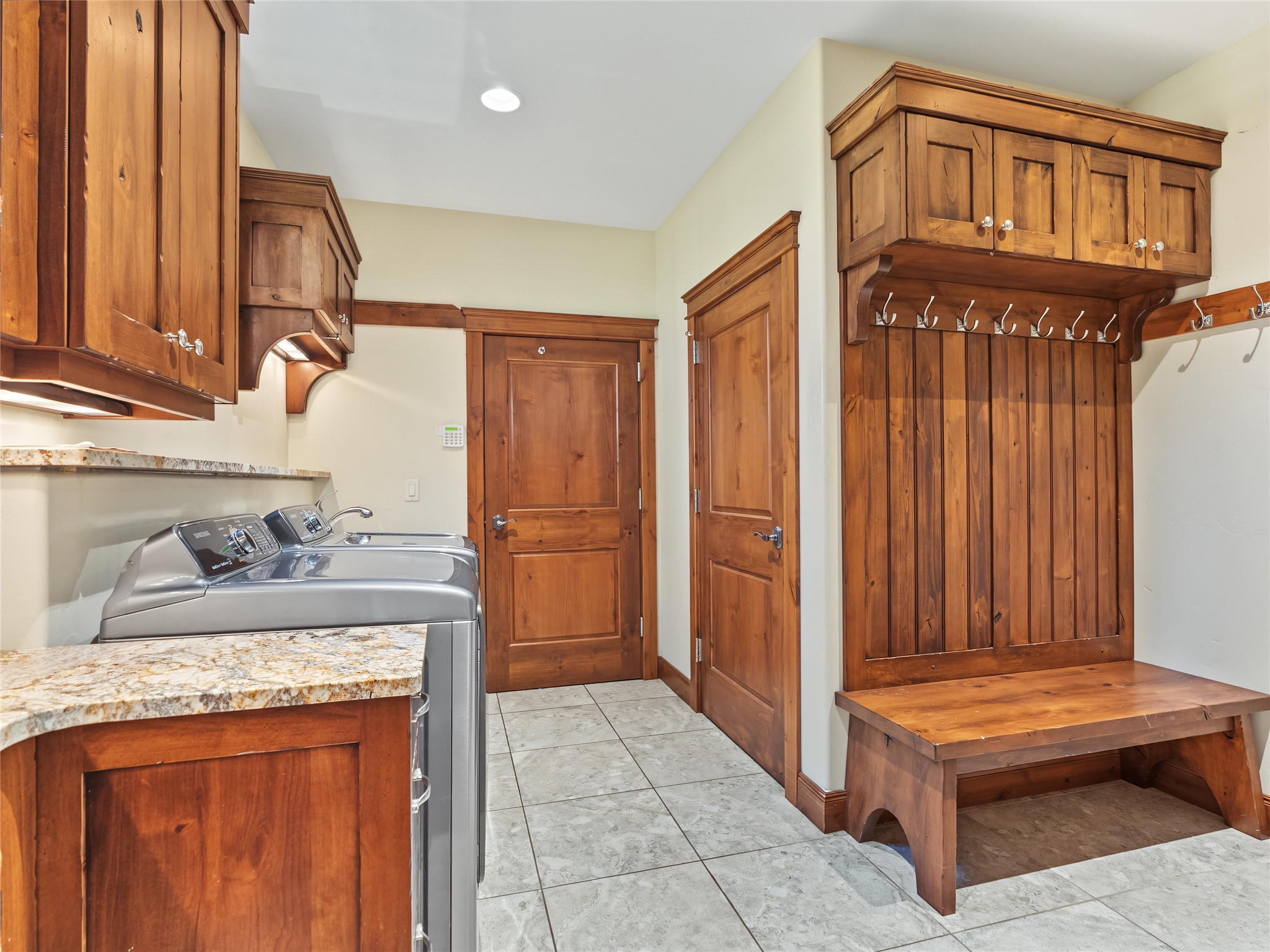 Laundry room with wood cabinets, washer and dryer, and a built-in coat rack and bench.