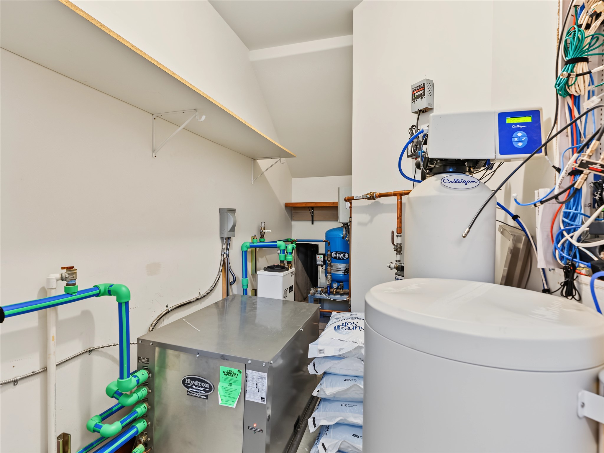 Utility room with a Culligan water softener, water-treatment equipment, and colorful plumbing.