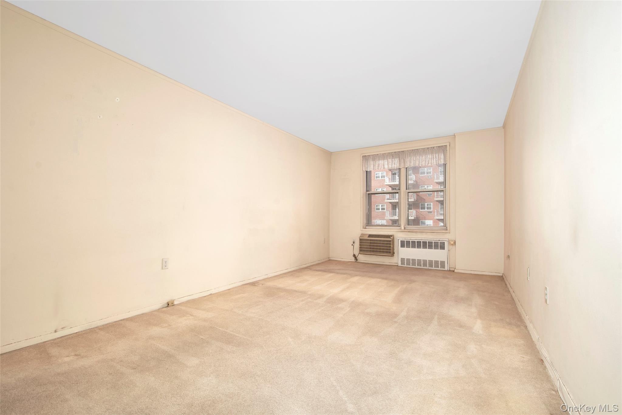 Empty carpeted room with a window, blinds, and two air-conditioning units.
