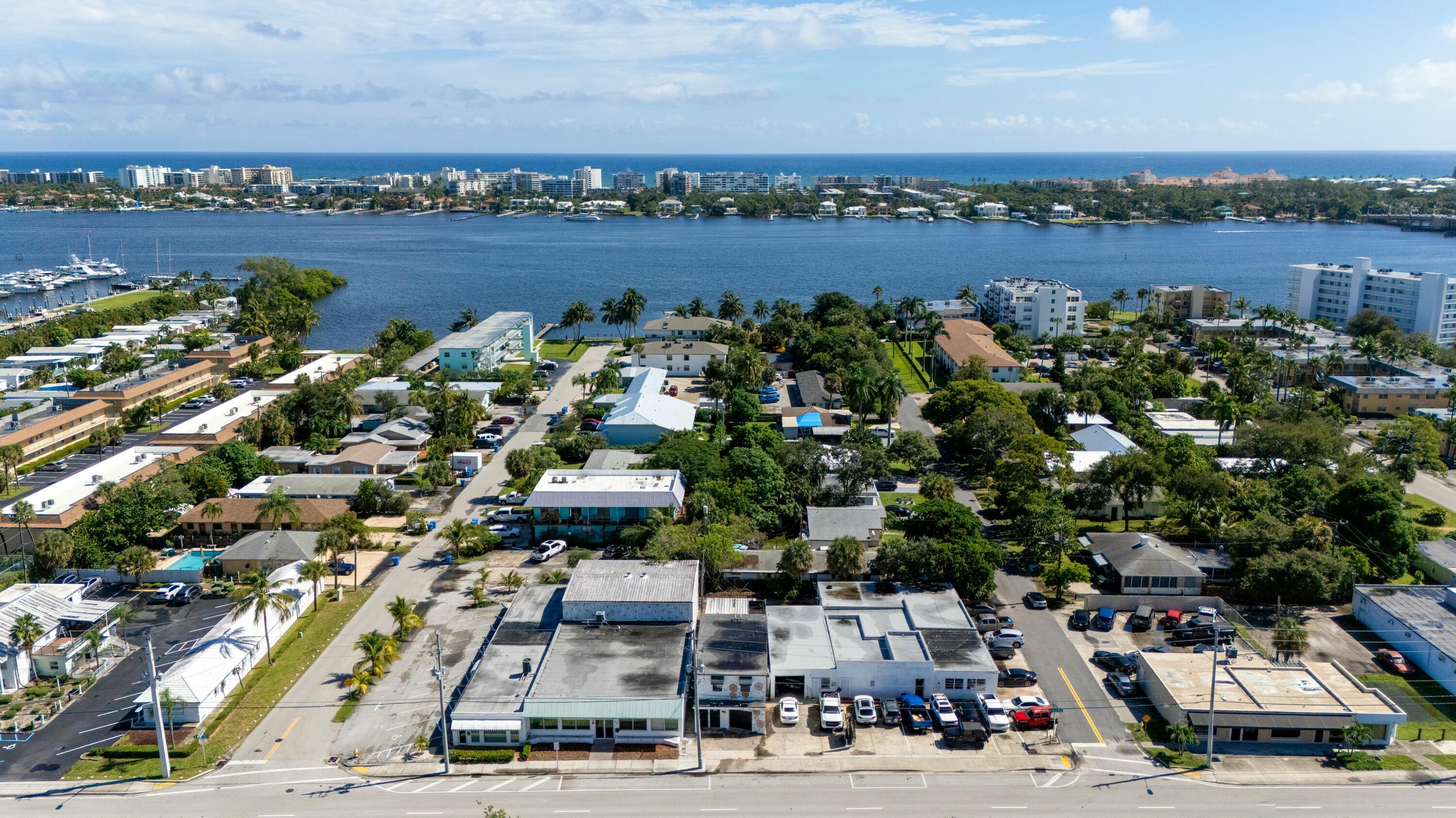Aerial view of a coastal neighborhood, marina, and waterway with the ocean beyond.