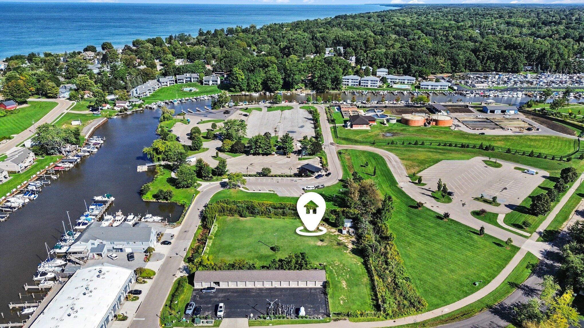 Vacant green parcel beside a marina, with a wooded shoreline and lake in the distance.
