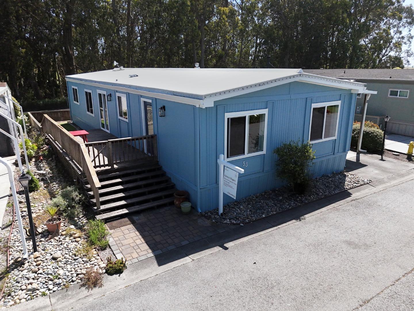 Blue single-story home with white trim, a flat roof, and a raised wooden deck and stairs.