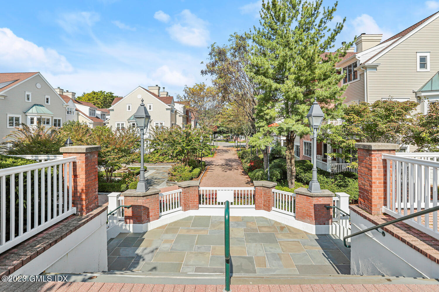 Condominium courtyard with a brick walkway, landscaped gardens, and light-sided buildings.