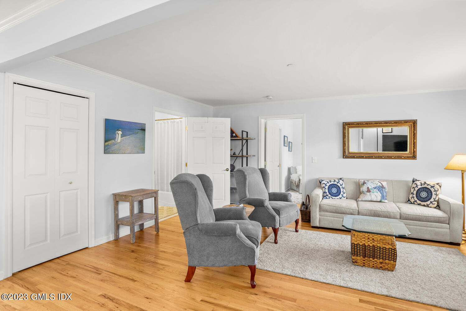Living room with gray armchairs, a light sofa, a large rug, and hardwood floors.