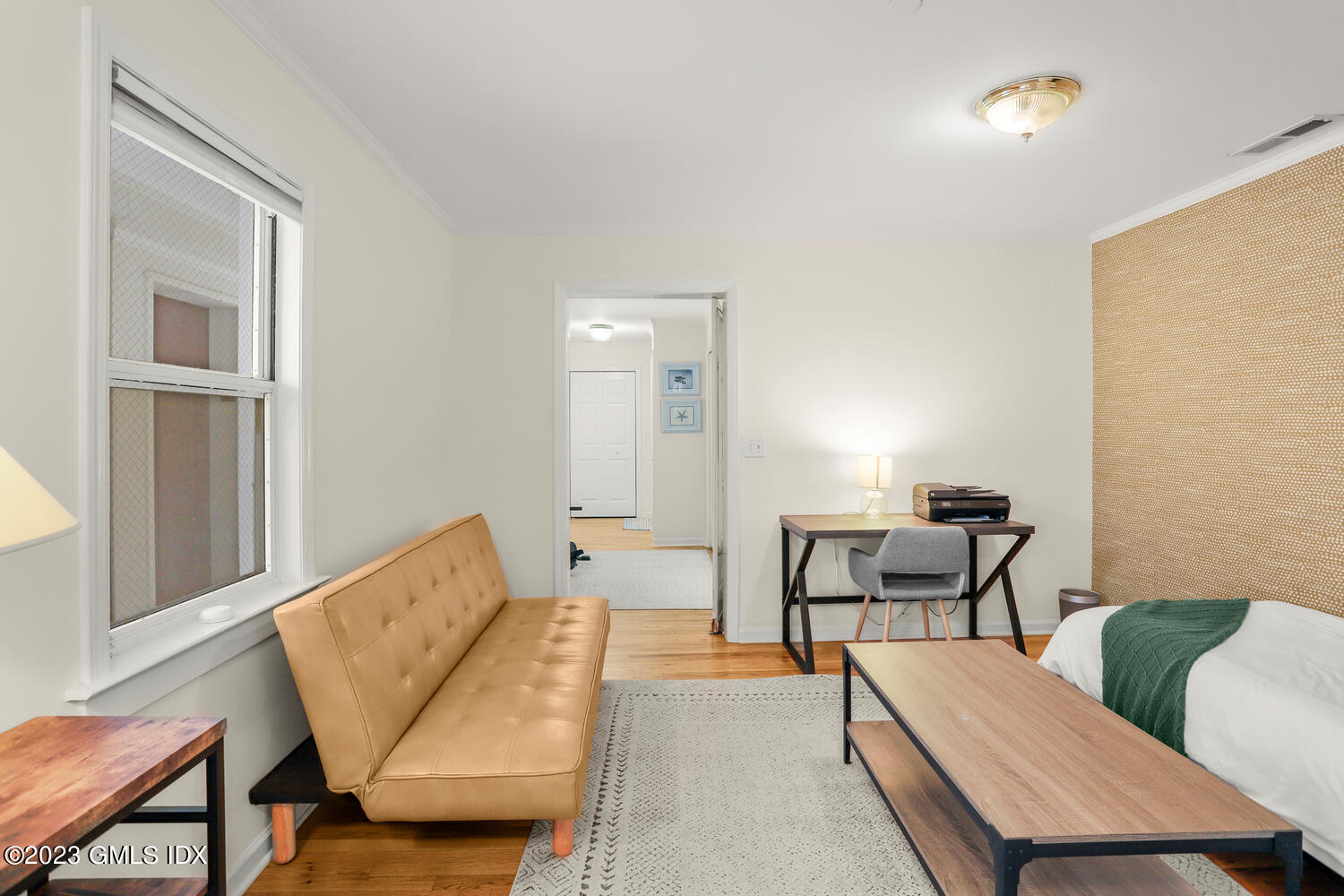 Furnished bedroom with a tan sofa, desk, and patterned accent wall.
