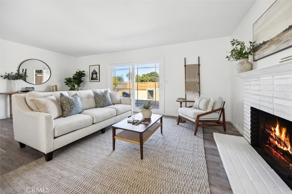 Living room with a white sofa, sliding glass doors, and a lit brick fireplace.