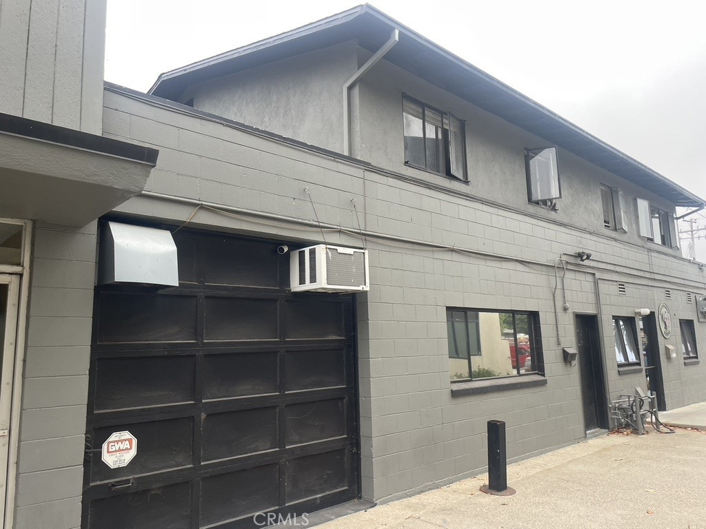 Two-story gray commercial building with a large black garage door and upper-floor windows.