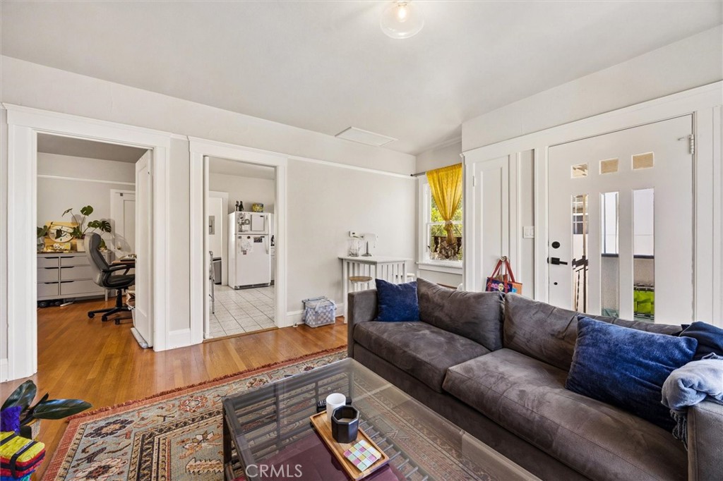 Living room with a gray sectional, blue cushions, glass coffee table, and hardwood floors.