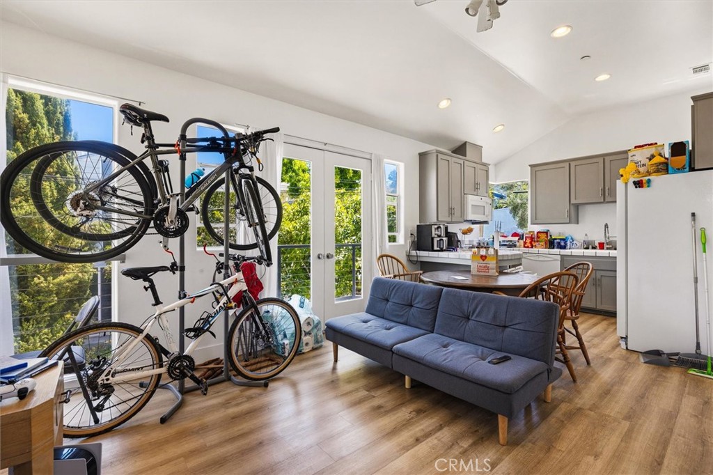 Open kitchen and living area with a blue sofa and bicycles parked beside large windows.