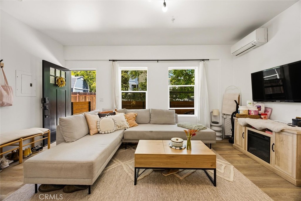 Furnished living room with a beige sectional, wood coffee table, and windows overlooking greenery.