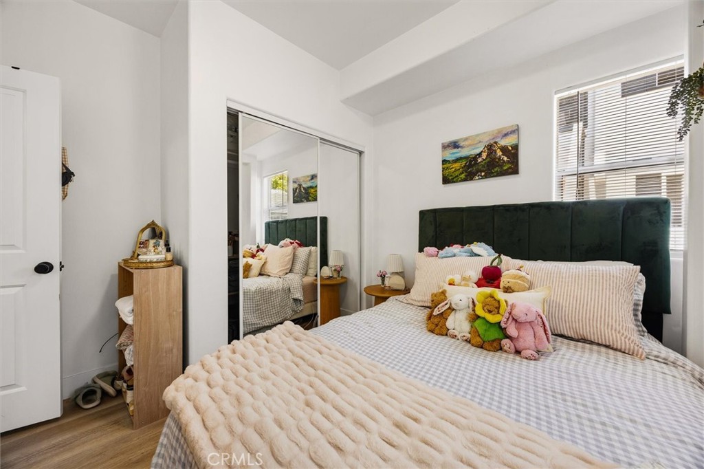 Bedroom with a dark green headboard, mirrored closet doors, and plush toys on the bed.