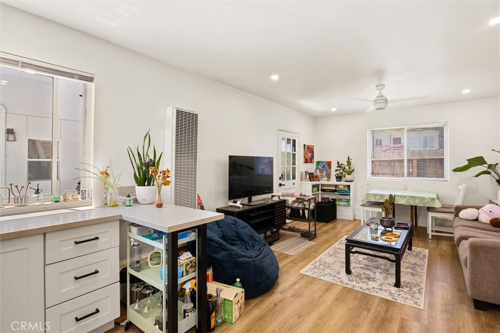 Open-plan living and kitchen area with a white island, wood floors, and a TV seating area.