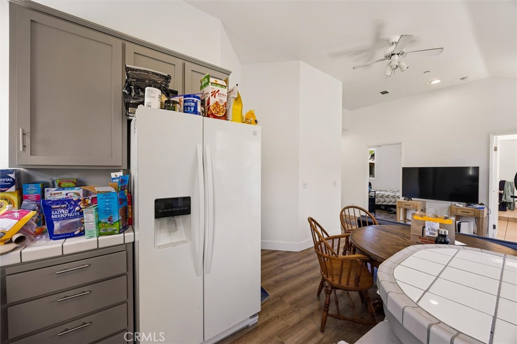 Kitchen with gray cabinets and a white refrigerator beside a round wooden dining table.
