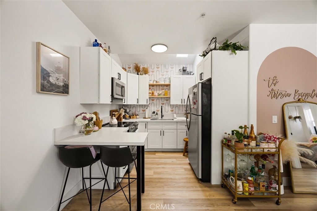 Kitchen with white cabinets, a peninsula breakfast bar, black stools, and stainless steel appliances.