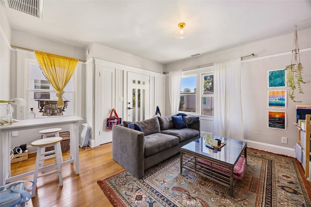 Living room with a gray sofa, patterned rug, and a small breakfast counter with stools.
