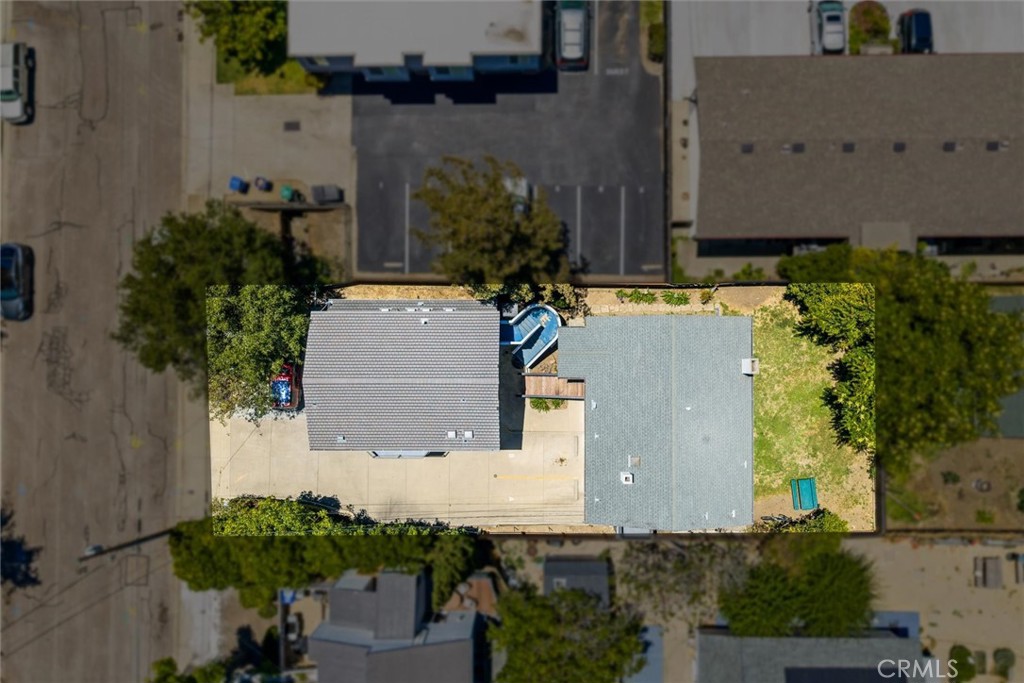 Aerial view of two roofed structures, a grassy yard, and a small blue pool.
