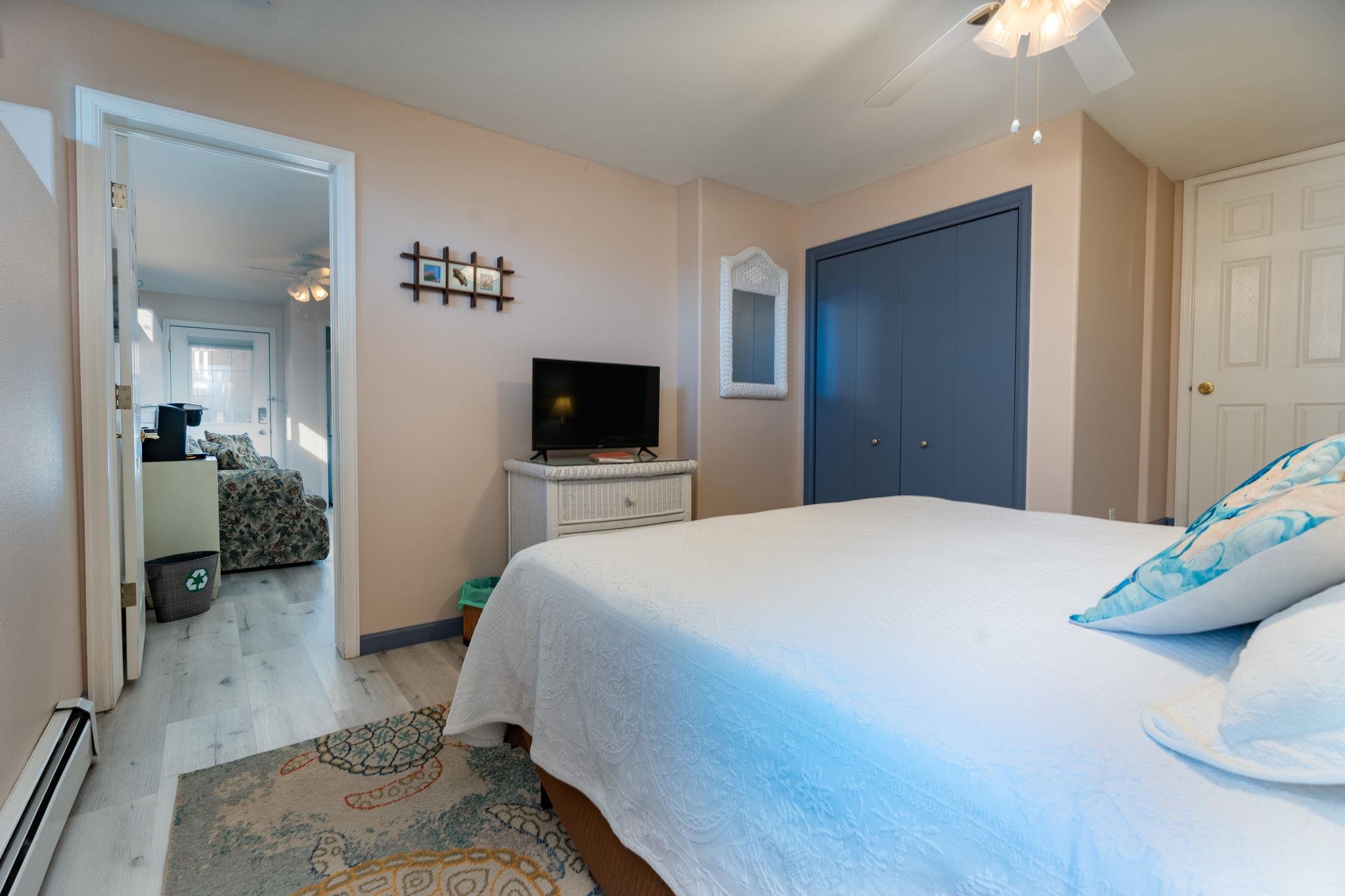 Bedroom with a white bed, blue closet doors, and a television beside an open doorway.