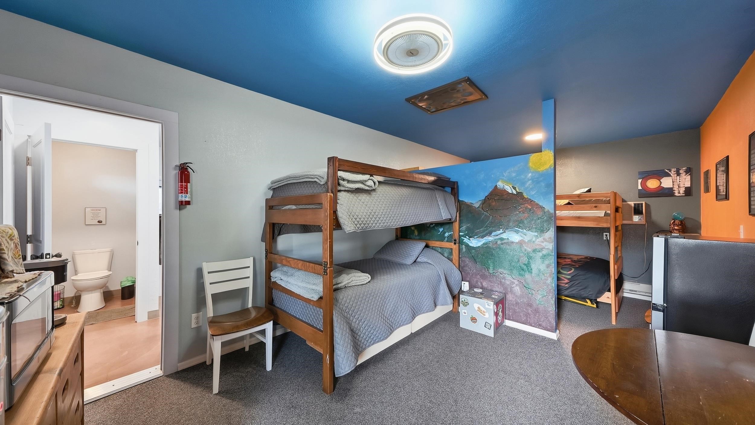 Bedroom with two wooden bunk beds and a painted mountain scene divider.