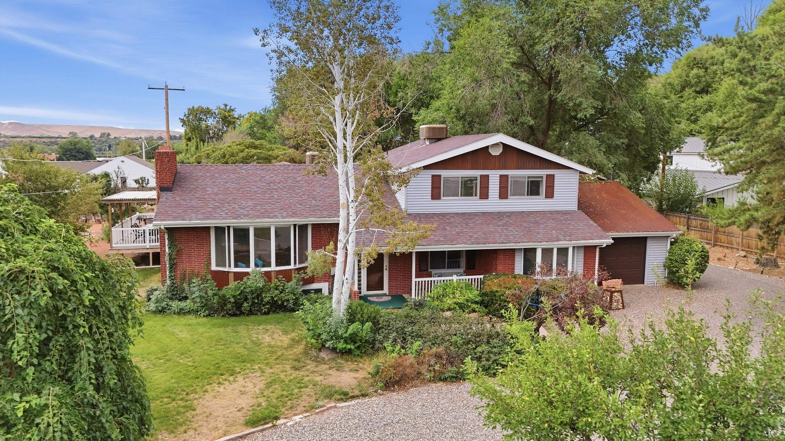 Two-story brick-and-siding home with a covered porch, attached garage, and gravel driveway.