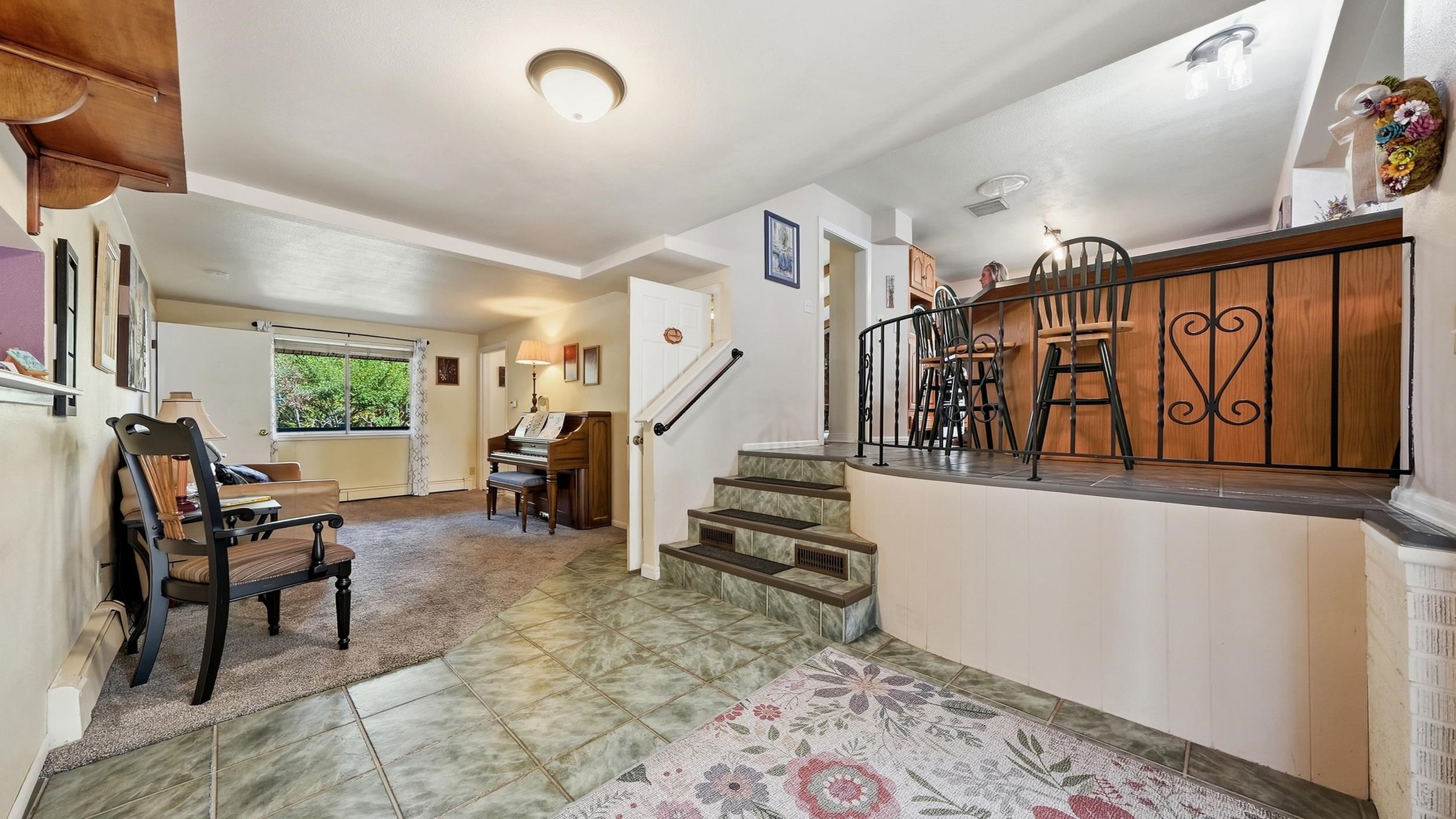 Furnished interior with a piano, tiled floor, and raised counter with bar stools.