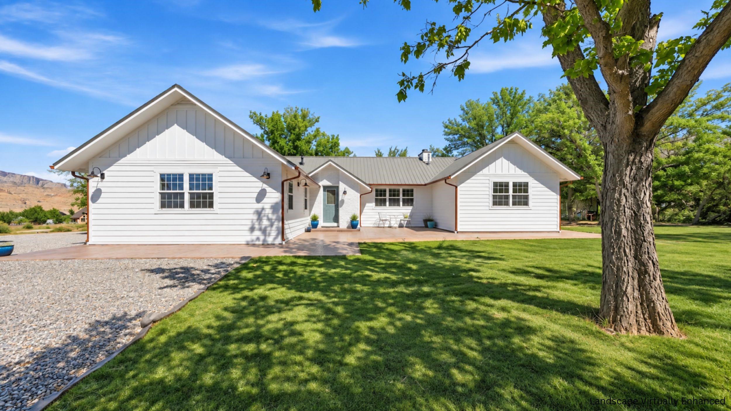White single-story home with a gray metal roof, broad lawn, and large shade tree.