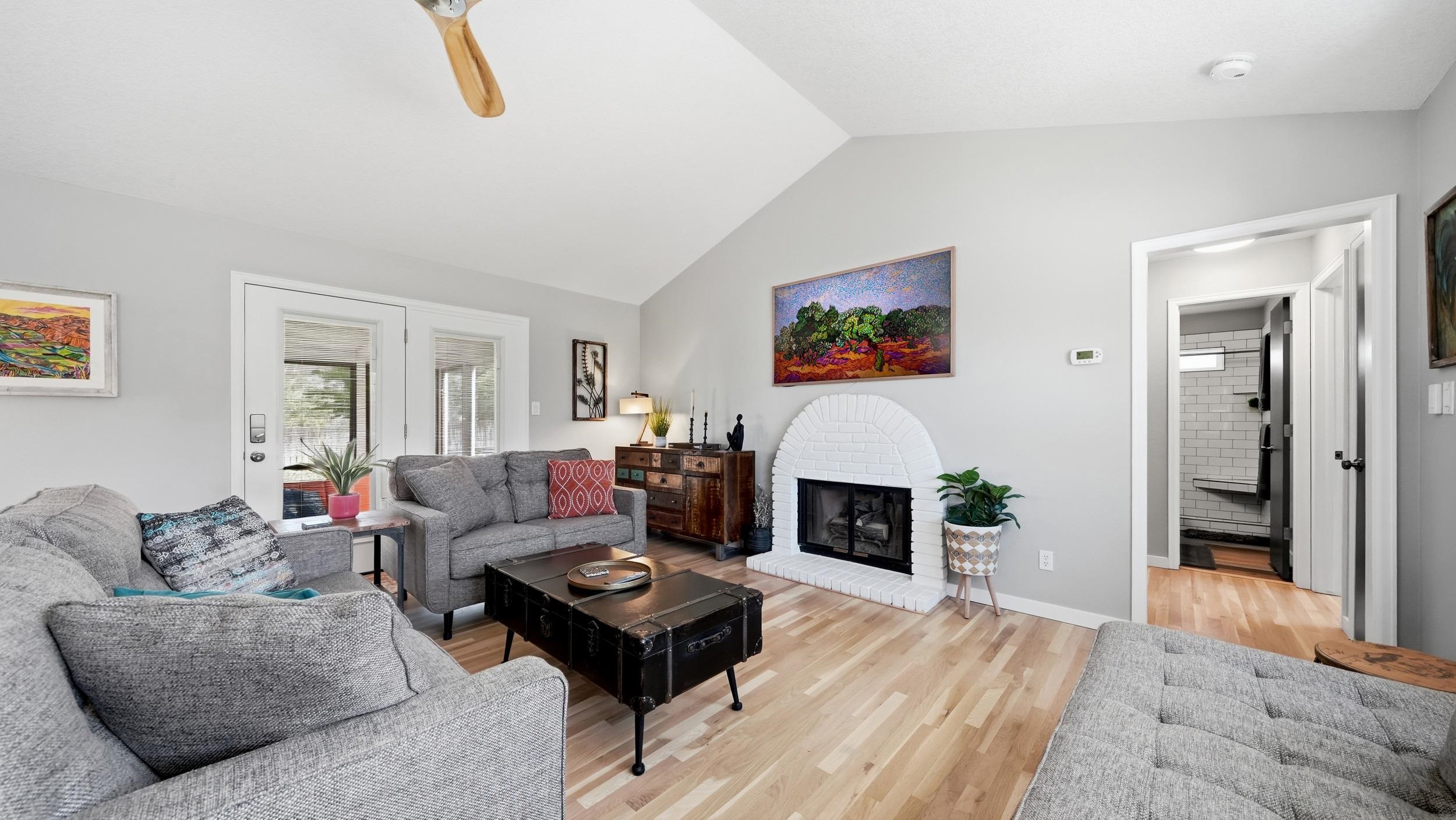 Living room with gray sofas, a white brick fireplace, and a black trunk coffee table.
