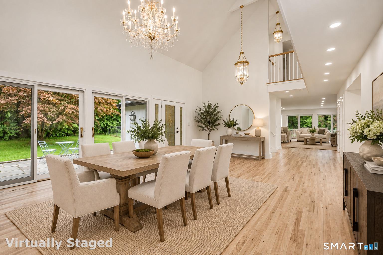 Dining room with a vaulted ceiling, crystal chandelier, long wood table, and sliding glass doors to the yard.