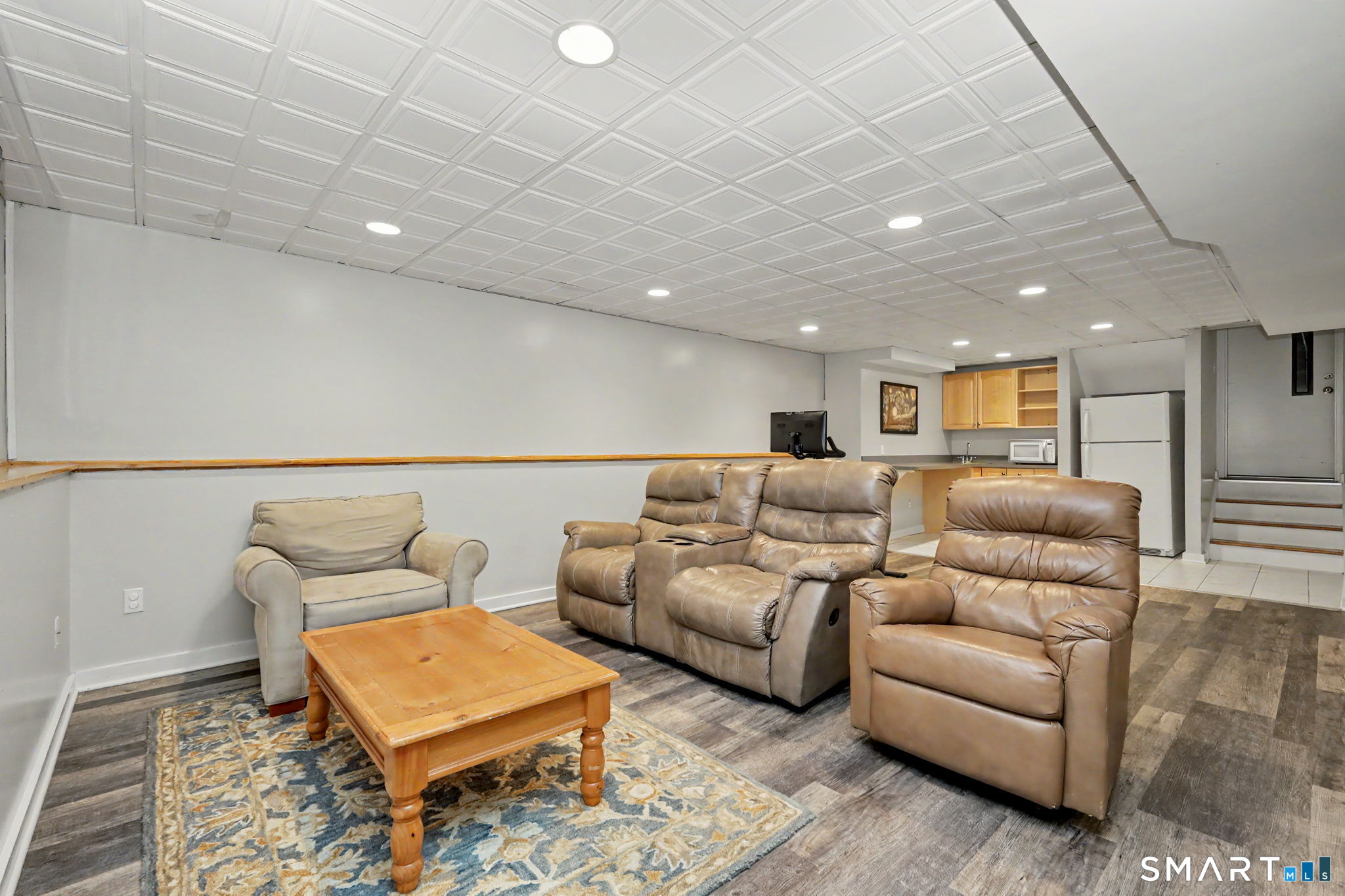 Finished basement family room with leather recliners, a coffee table, and a kitchenette.