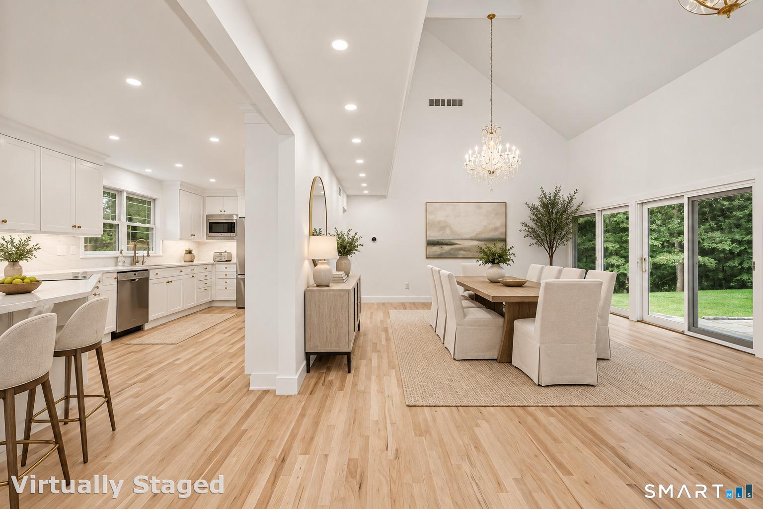 Open-plan kitchen and dining room with white cabinetry, vaulted ceiling, and sliding glass doors to the yard.