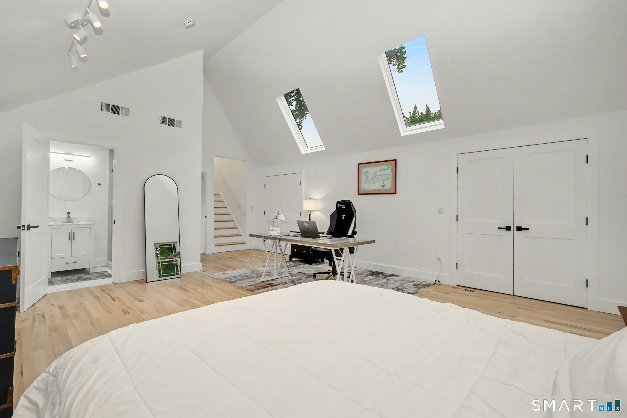 Bedroom with two skylights, a desk, and an open doorway to an en-suite bathroom.