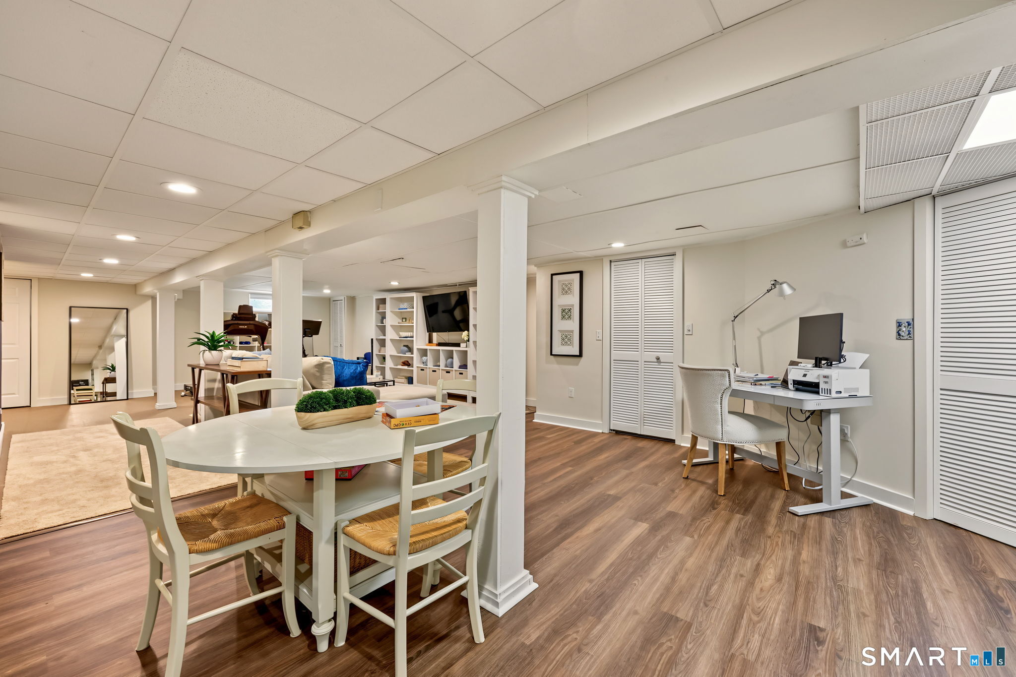 Furnished basement with a dining table, entertainment area, built-in shelves, and a home office desk.