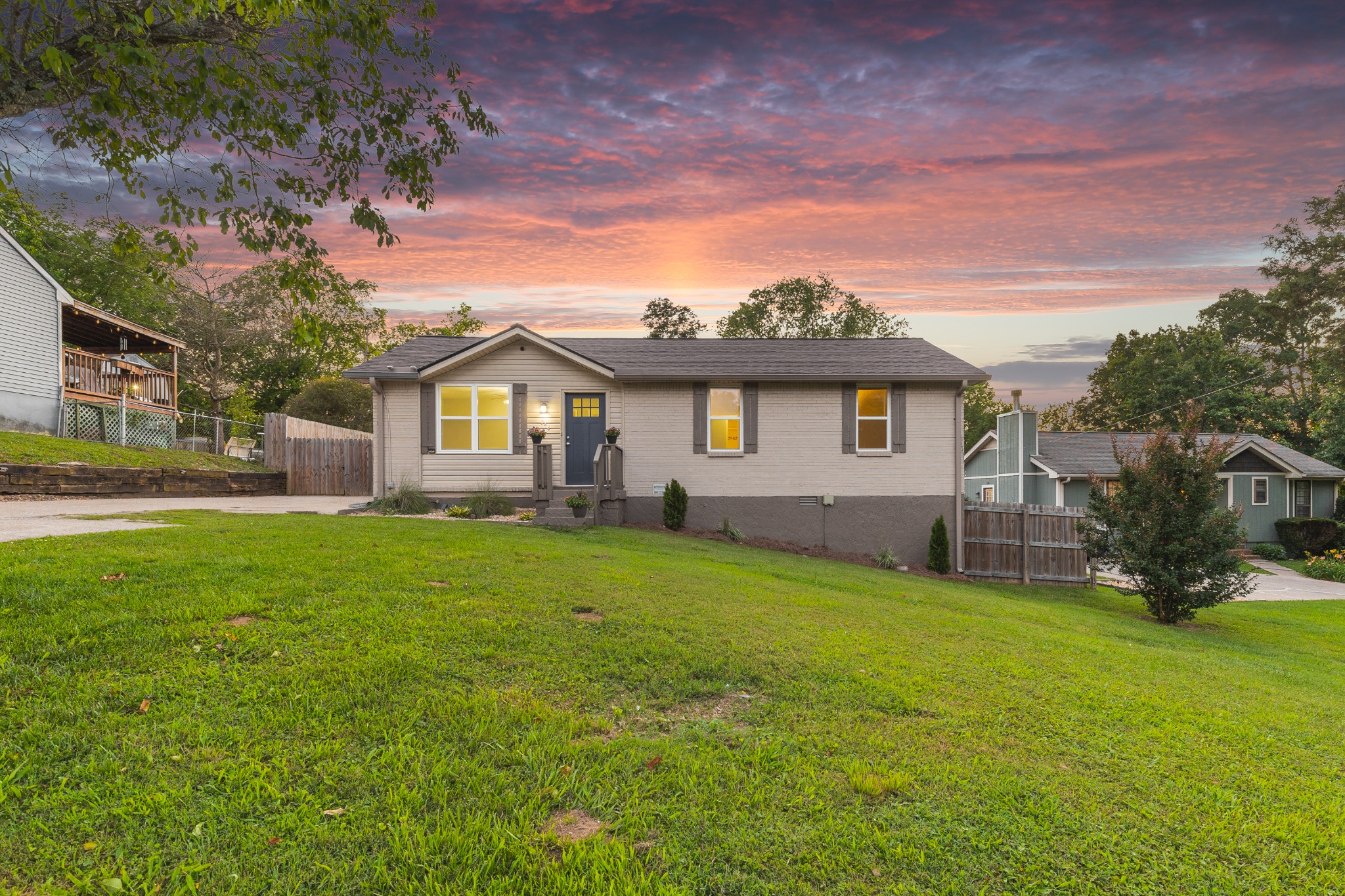 Single-story home with a broad lawn beneath a vivid pink sunset sky.