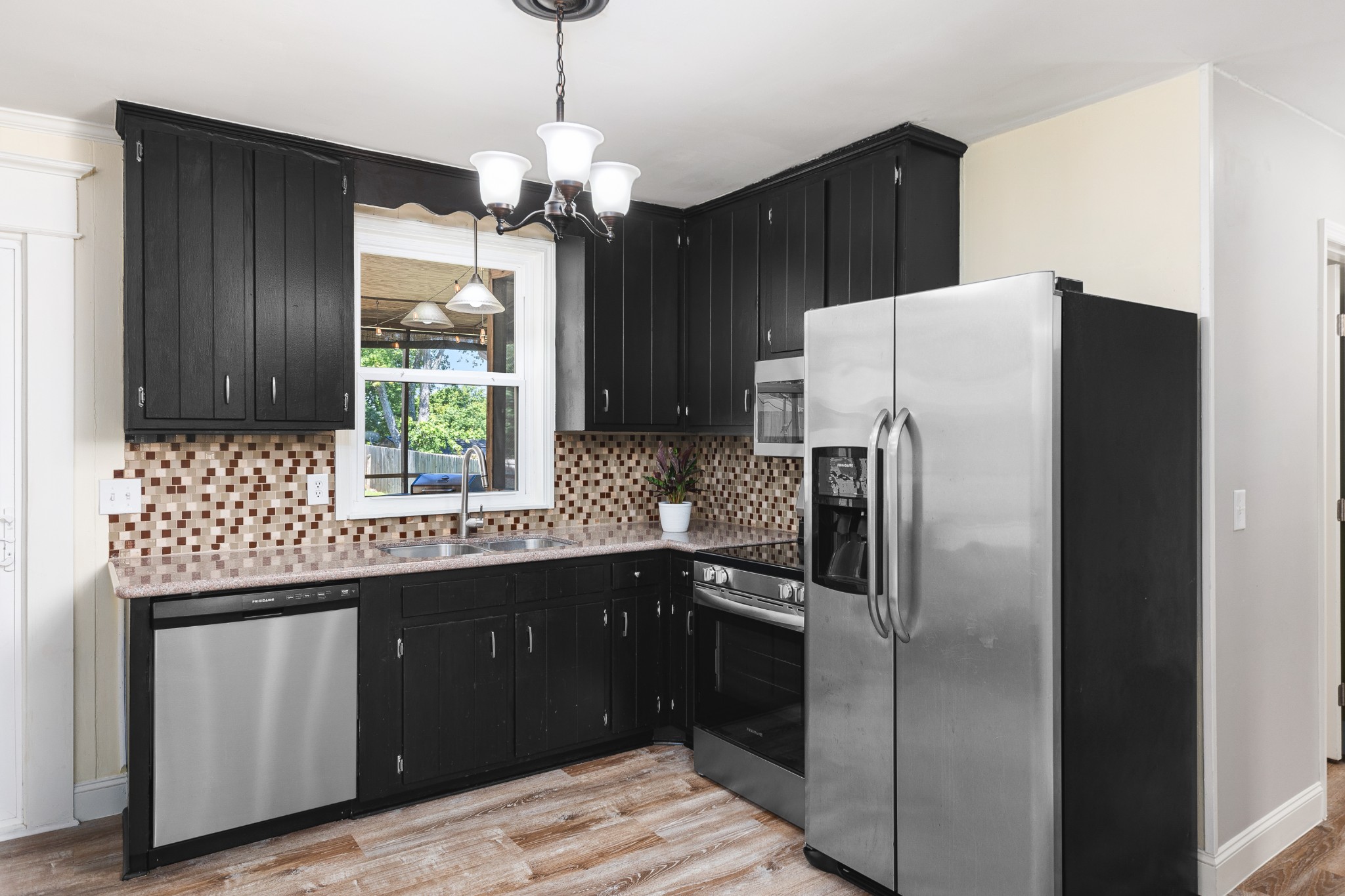 Kitchen with black cabinets, mosaic tile backsplash, and stainless steel appliances.