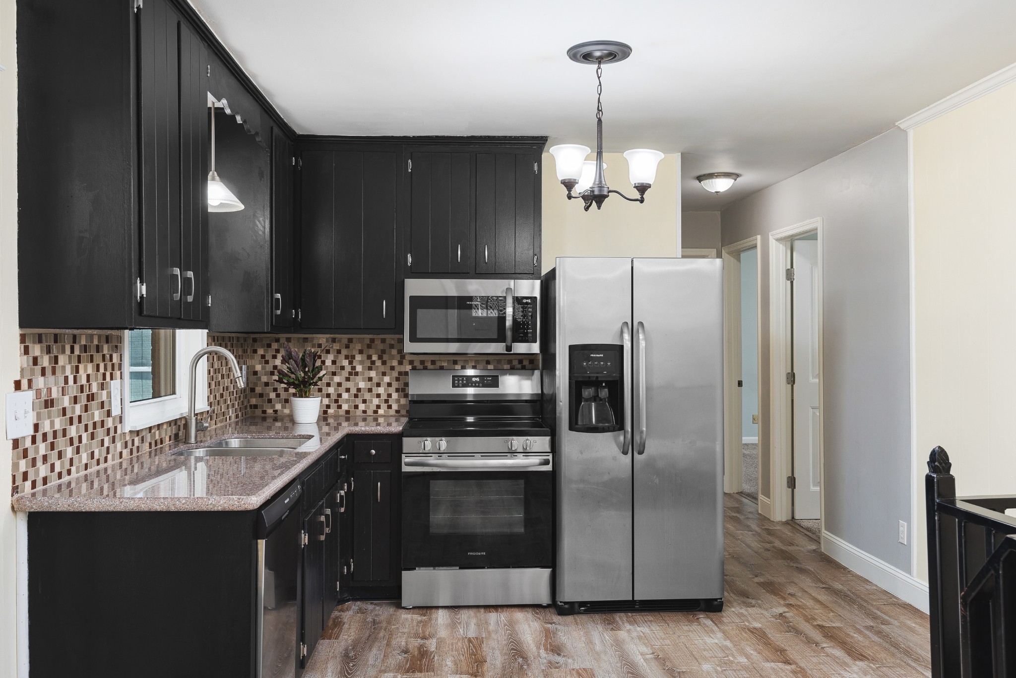 Kitchen with black cabinets, stainless steel appliances, and a mosaic tile backsplash.