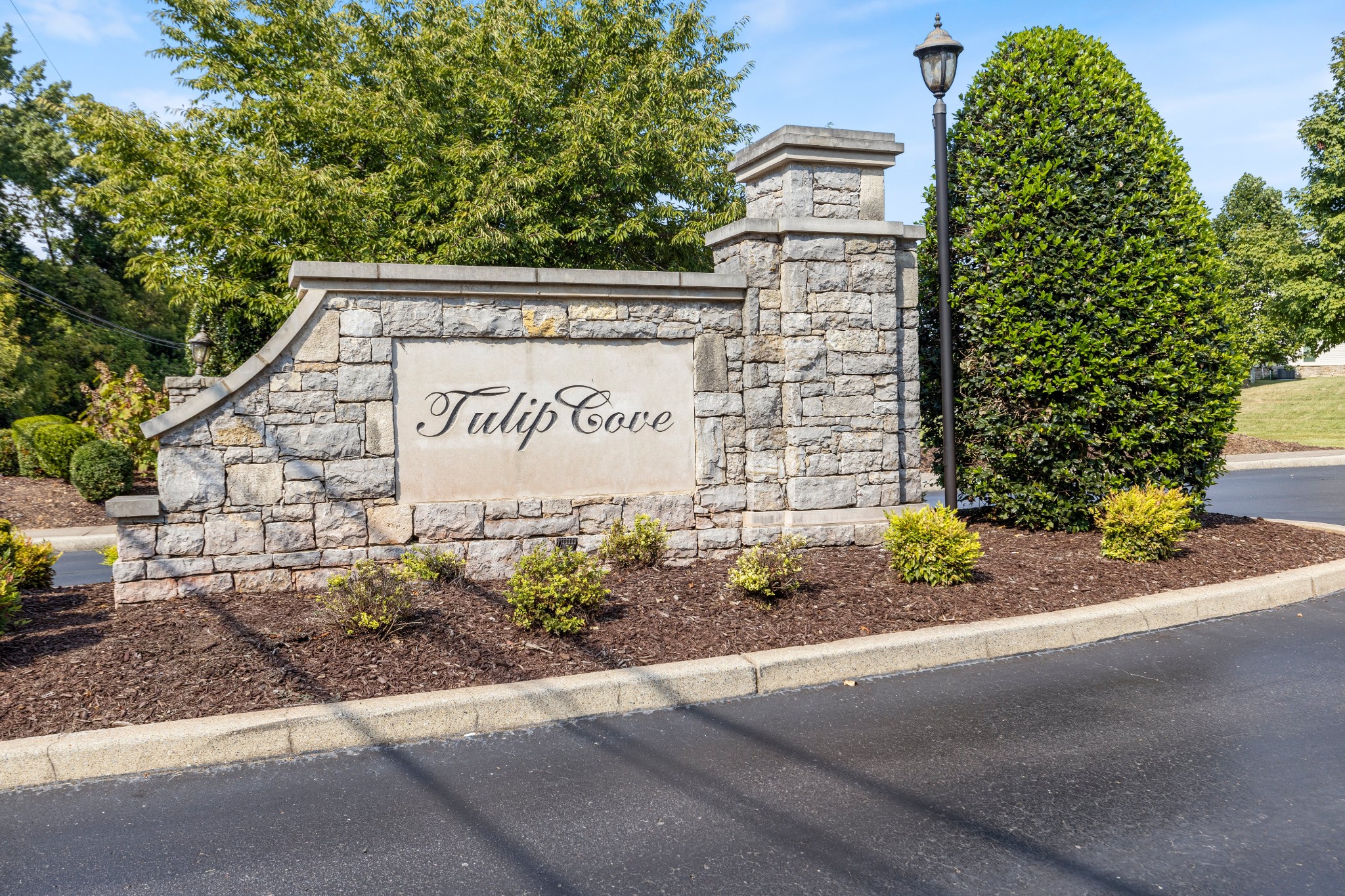 Tulip Cove community entrance sign set in a stone monument among landscaped shrubs.