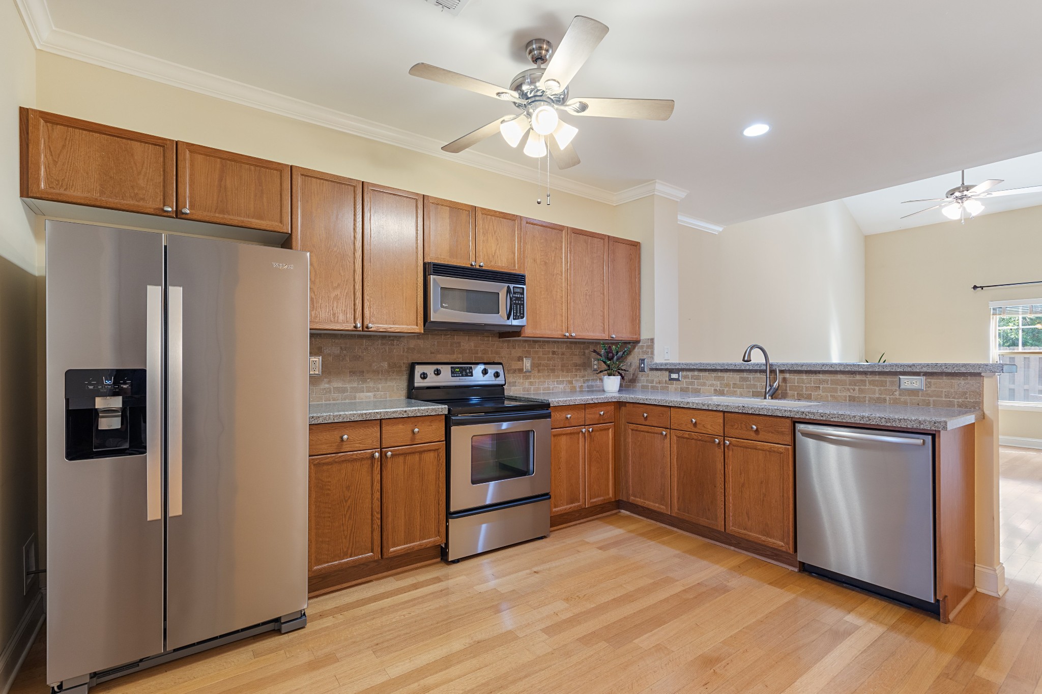 Kitchen with wood cabinets, granite counters, stainless steel appliances, and hardwood floors.
