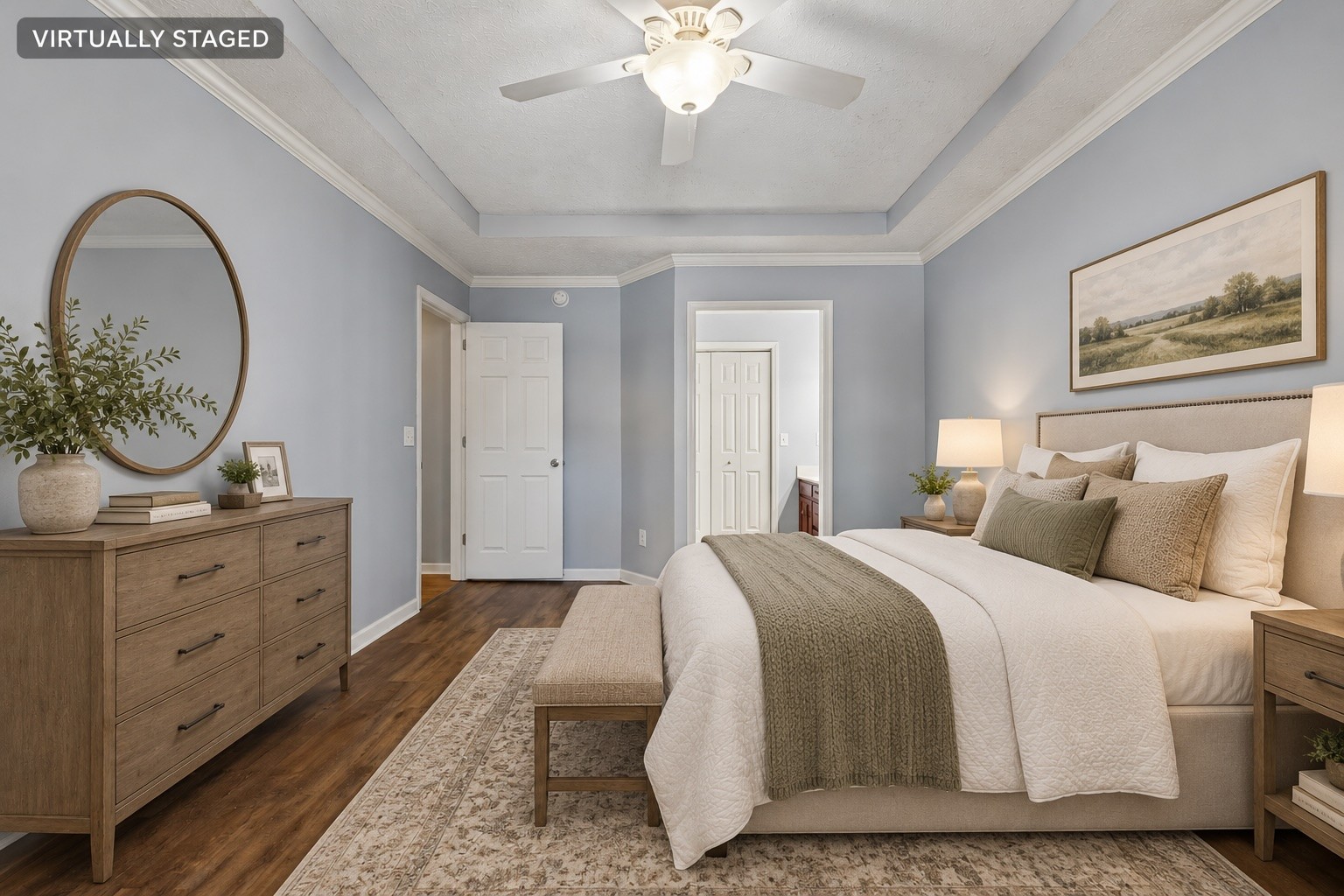Virtually staged bedroom with a neutral upholstered bed, wood dresser, and oval mirror.