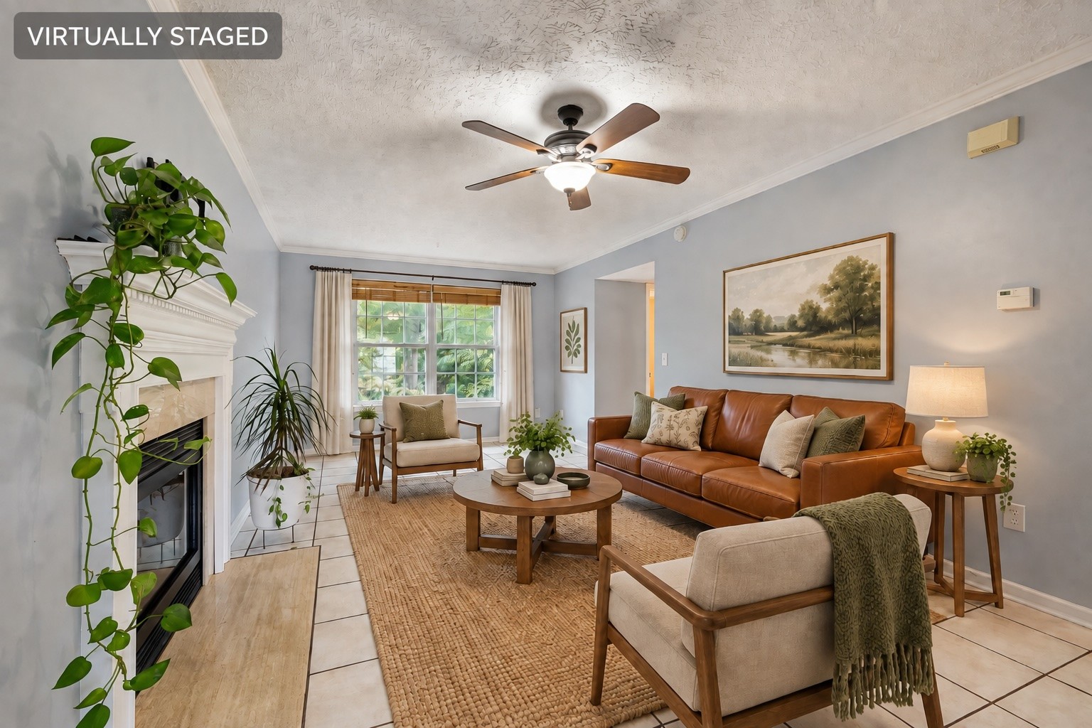 Living room with a white fireplace, leather sofa, and round coffee table, virtually staged.
