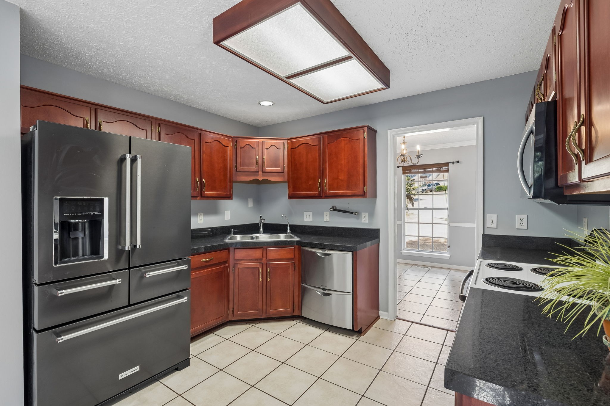 Kitchen with reddish-brown cabinets, dark countertops, and stainless steel appliances.
