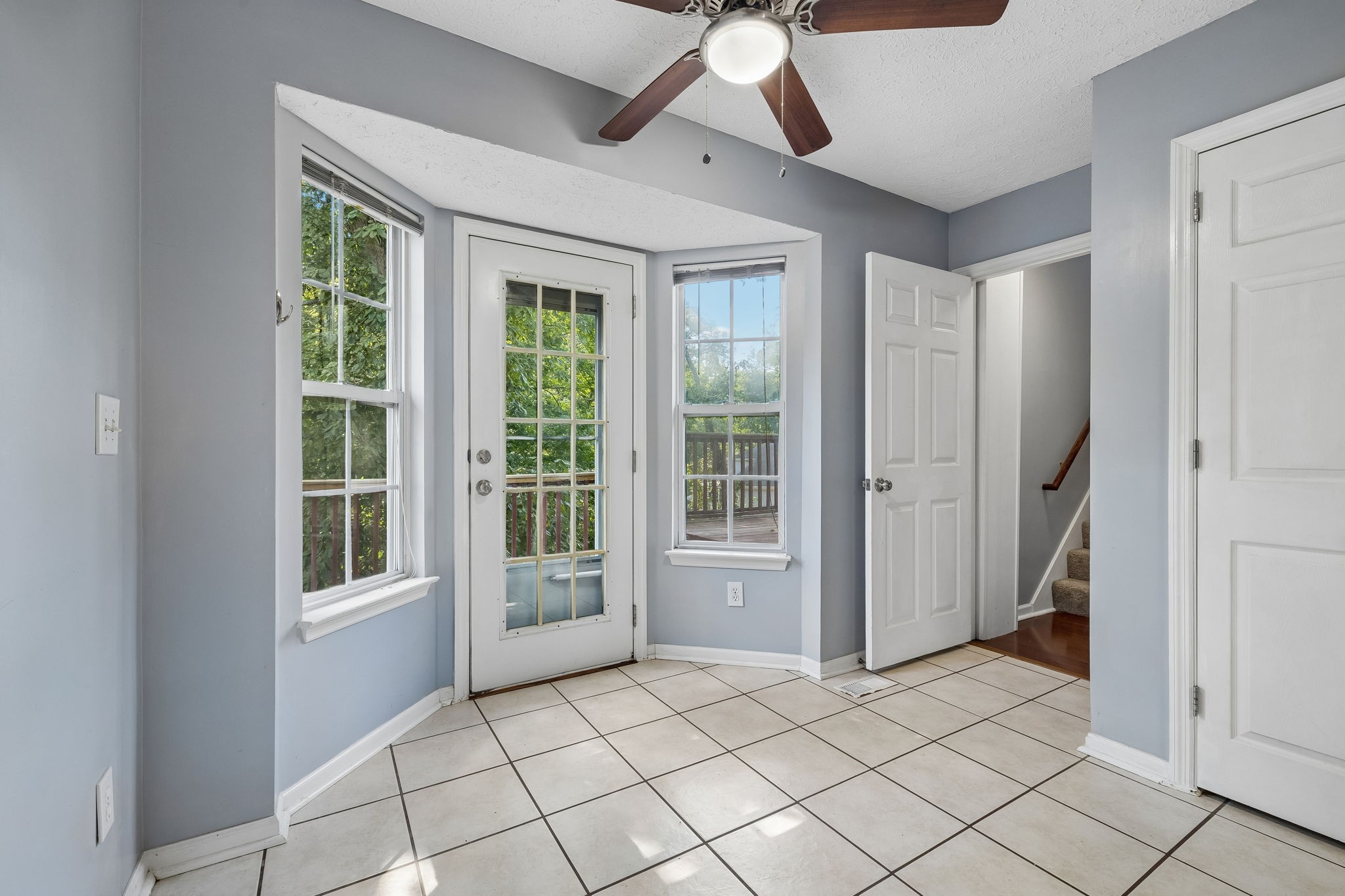 Tiled entryway with a glass-paneled door, two windows, and an open doorway to the stairs.