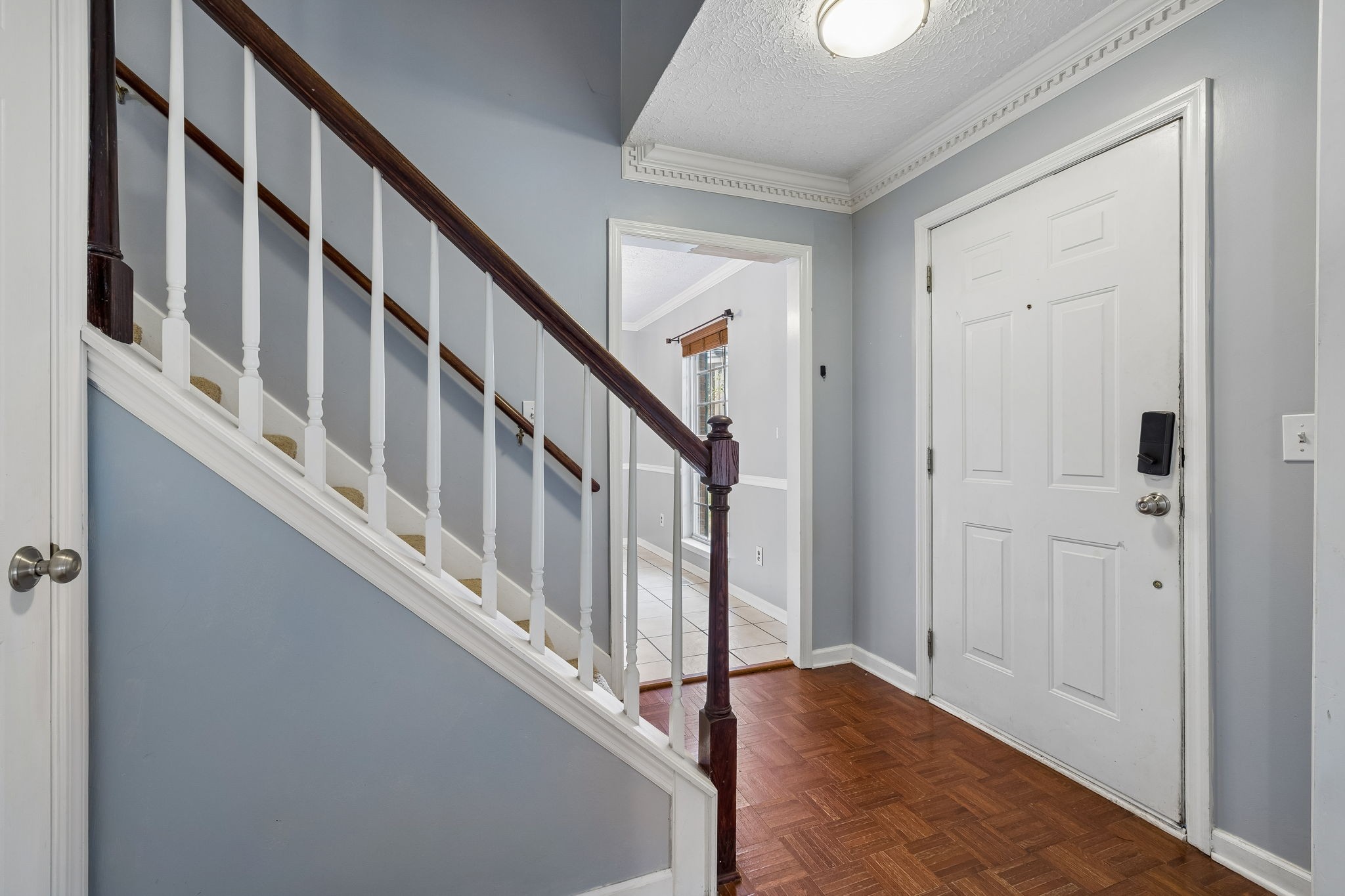 Entry hall with parquet flooring and a staircase beside the white front door.